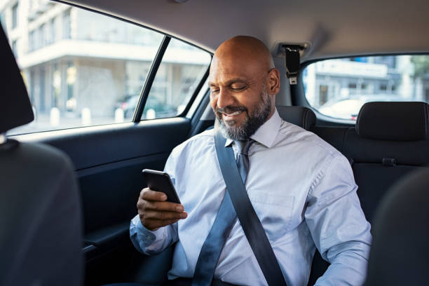 homme d’affaires d’âge mûr utilisant le téléphone dans la voiture - move back photos et images de collection