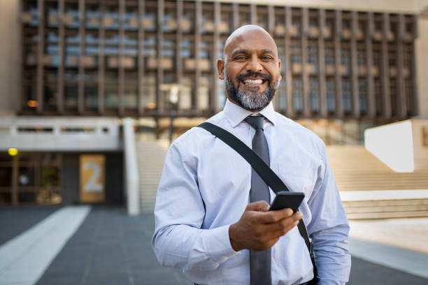 счастливый зрелый бизнесмен с помощью телефона - walking people business travel business стоковые фото и изображения