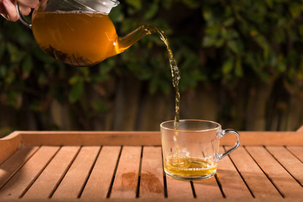 istock Pouring tea from a teapot into a cup on a blurred background of nature 1138563273