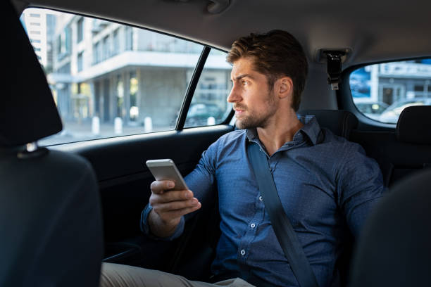 スマートフォンを使って車の中に座っている人 - businessman checking the time men male ストックフォトと画像