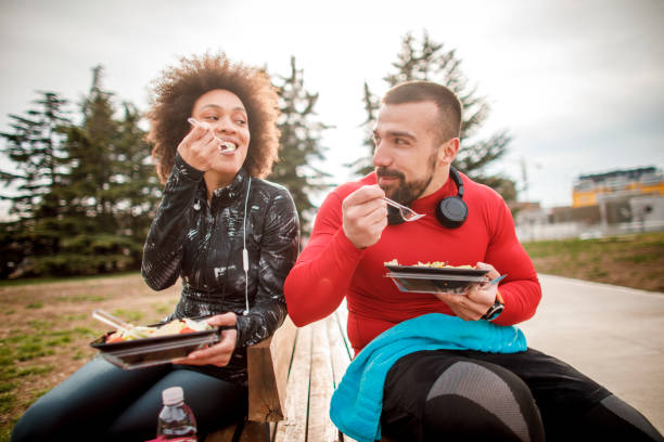 istock Young couple having a protein salad while sitting next to each other on a park bench 1138566451