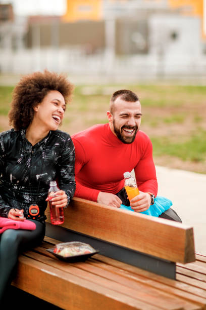 istock Young athletic couple hydrating themselves and having a laugh while taking a break after exercising in a city park 1138566886