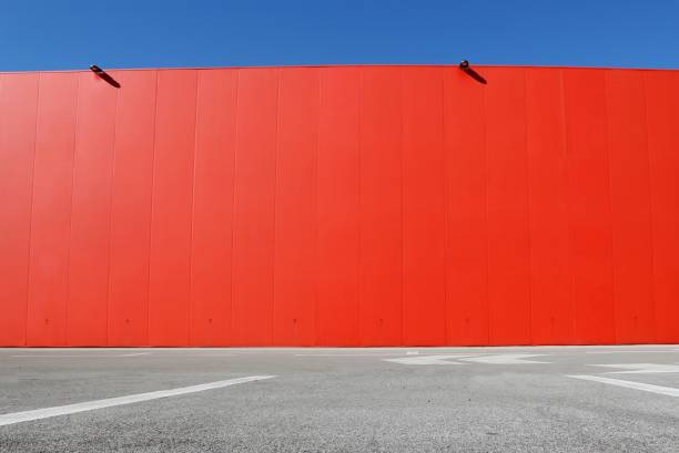 istock Bright red aluminium cladding wall with an asphalt road in front. Background for copy space 1138567886