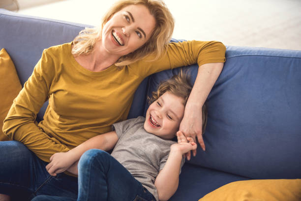 istock Joyful mother and cute boy are rejoicing together on couch 1138568070