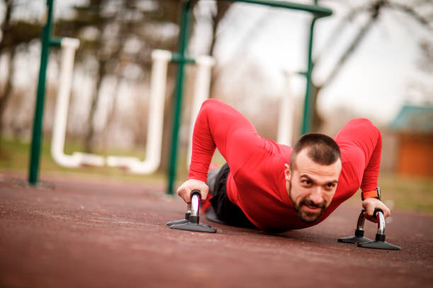 istock Muscular athletic man doing a push-up workout using grip stands in a city park 1138569664