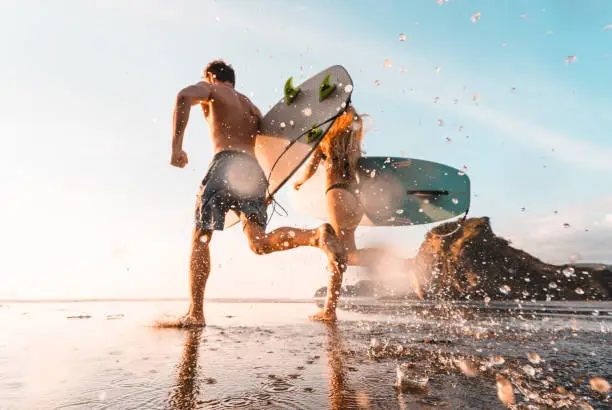 Photo of Surfers with surfboards running towards beach.