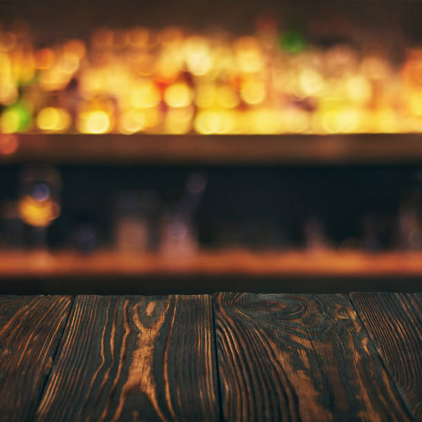 istock Empty wooden bar table top with defocused background. Bar counter table in front of blurred beaverages and drinks 1138577355