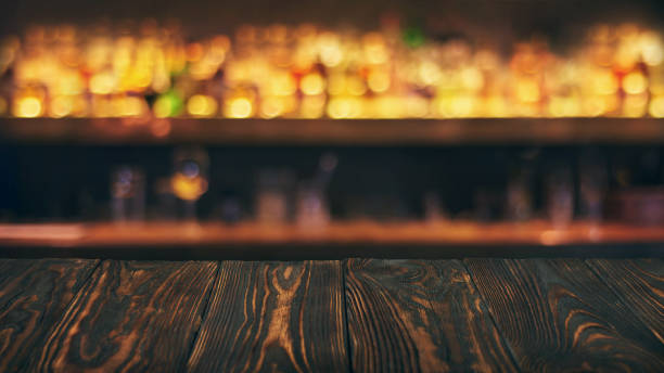 istock Empty wooden bar table top with defocused background. Bar counter table in front of blurred beaverages and drinks 1138577356