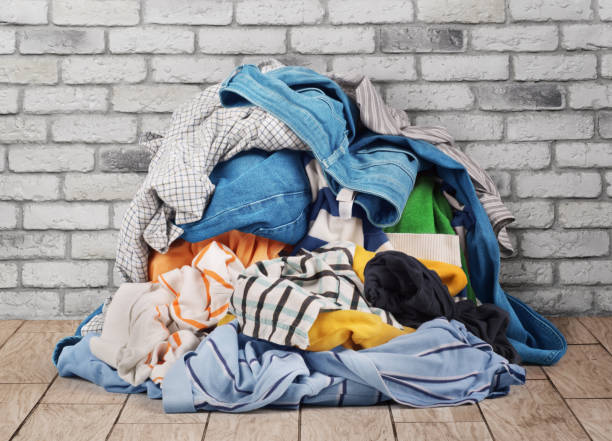 pile of clothes on floor near brick wall - monte roupa imagens e fotografias de stock