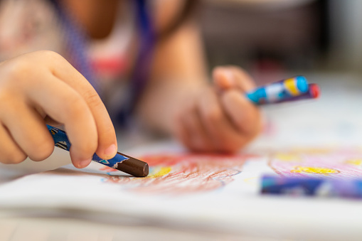 Close up of little hands coloring with Crayon