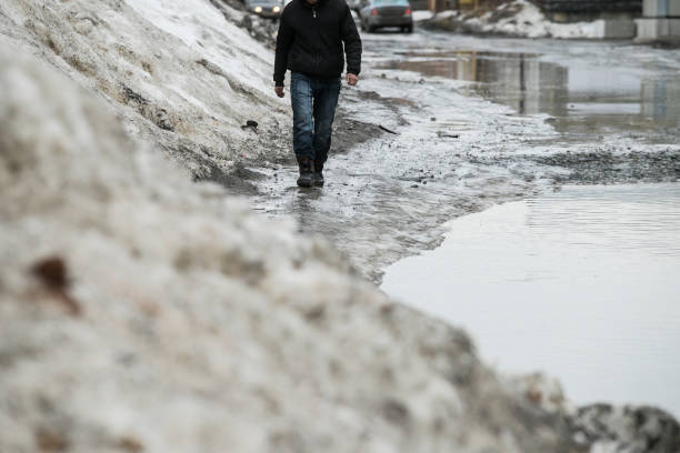 istock warming in early spring, snow melts turning into slush and puddles underfoot, which bypass the pedestrians walking on the sidewalk and crossing the road with wet feet 1138585412