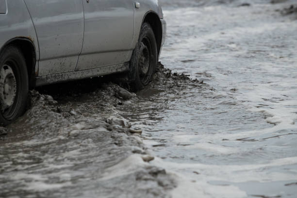 istock Poor road condotions - car wheel in melting show puddle. 1138586123