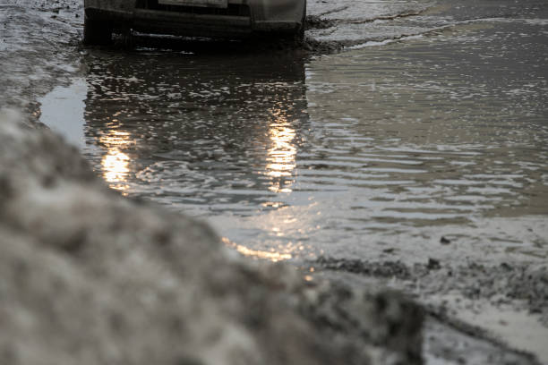 istock Poor road condotions - car wheel in melting show puddle. 1138586278