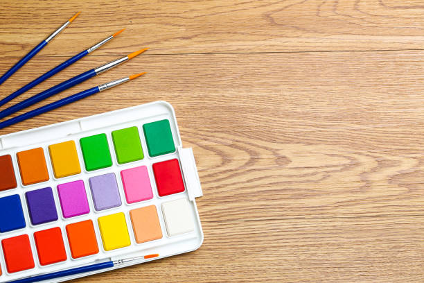 istock Set of solid watercolors and paintbrush on wooden table background 1138587365