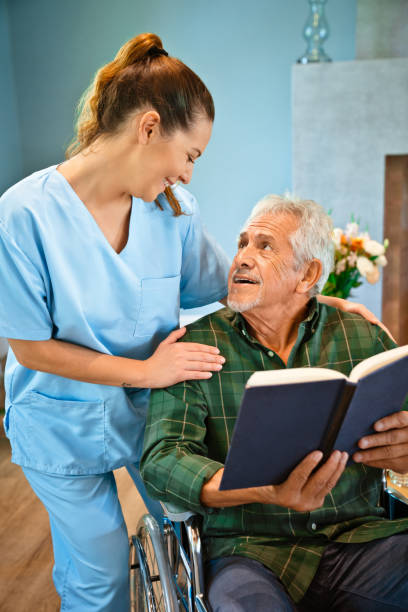 istock Disabled senior man with book looking at nurse 1138592345