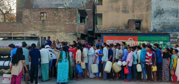 People queue for taking water from Delhi Jal board tanker in the early morning. New Delhi, India - March 27 2019: People queue for taking water from Delhi Jal board tanker in the early morning. This shows the water scarcity around the densely populated societies. water crisis stock pictures, royalty-free photos & images