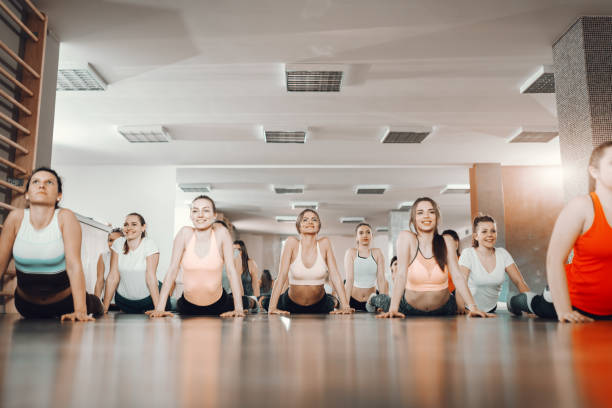 grupo de mujeres alegres haciendo cobra pose en el piso del gimnasio. estira el punto de frenado hasta un lugar donde tu oponente no pueda encontrarlo. - exercising sports training sport gym fotografías e imágenes de stock