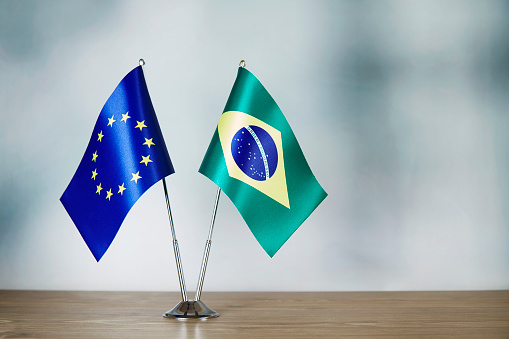 European Union and Brazilian flag standing on the table with defocused background