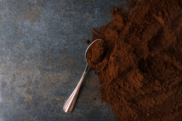 Ground coffee and spoon on grey surface,table.Concept of coffee preparation at the cafe Closeup of ground coffee against coffee pot and dark wall ground coffee stock pictures, royalty-free photos & images