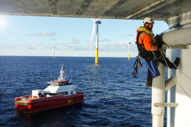 técnico de acesso por corda fazendo inspeção, reparando em plataforma offshore com proteção de embarcação de transferência - wind power wind turbine safety technology - fotografias e filmes do acervo