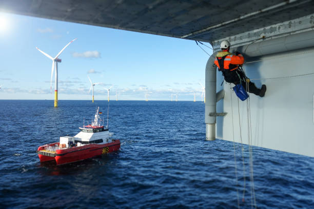 Rope access technician making inspection, repairing on offshore platform with transfer vessel guarding