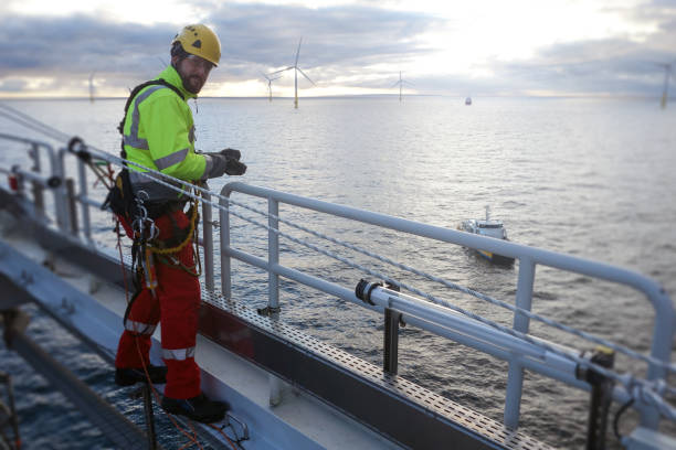 istock Rope access technician making inspection and repairs of railing with transfer vessel guarding 1138600673