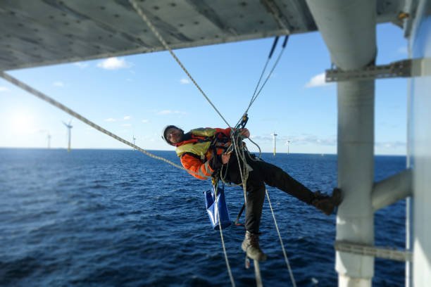 técnico de acesso por corda fazendo inspeção, reparando em plataforma offshore com proteção de embarcação de transferência - wind power wind turbine safety technology - fotografias e filmes do acervo