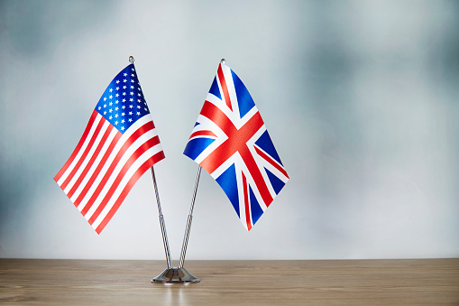 American and British flag standing on the table with defocused background