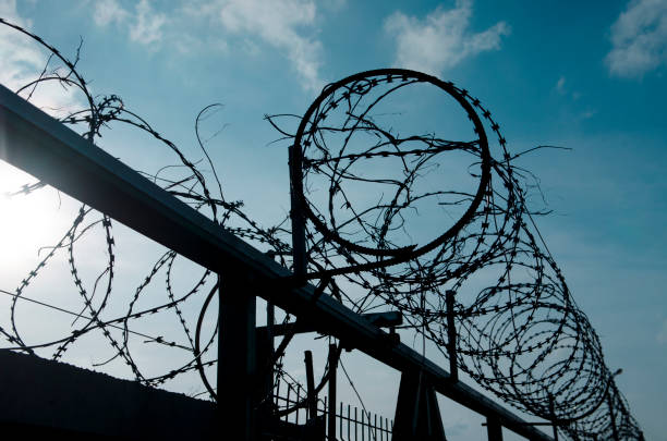 istock Metal barbed wire on a blue sky with white clouds 1138601461