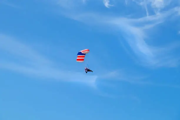 Photo of Pilot hang gliding on a blue sky  background.