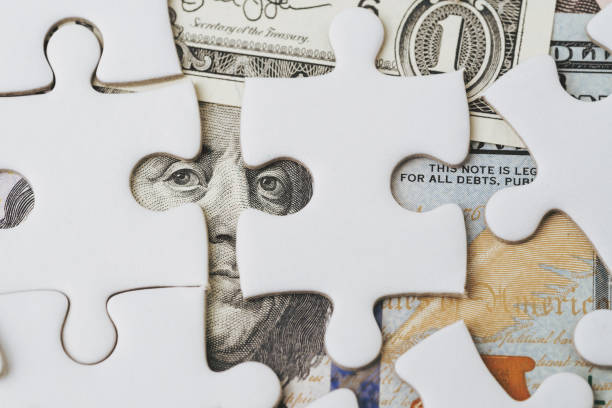 istock Solving the financial or business problem or idea for making money concept, white jigsaw puzzle game on US Dollar banknote with the eyes of Ben Franklin face 1138608385