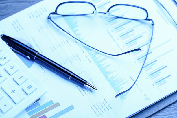 istock pen,glasses,calculator and business statistics on wooden table 1138608566