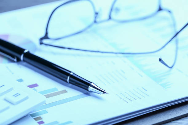 istock pen,glasses,calculator and business statistics on wooden table 1138608708