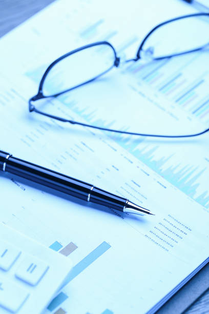 istock pen,glasses,calculator and business statistics on wooden table 1138608785