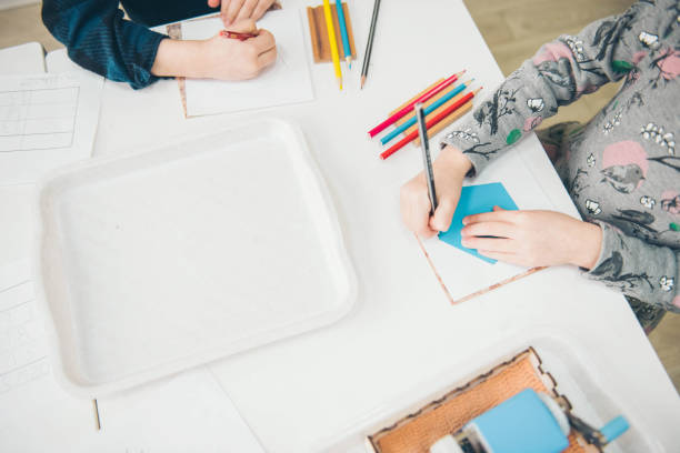 istock Montessori School. Learning materials in a montessori methodology school. Geometric materials. Color pencils. Little girls drawing on paper. 1138610306