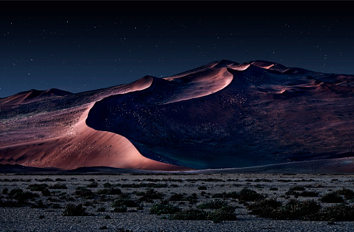 desert of namib at night with orange sand dunes and starry sky.