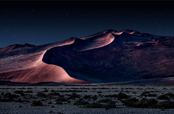 desert of namib at night with orange sand dunes and starry sky stock photo
