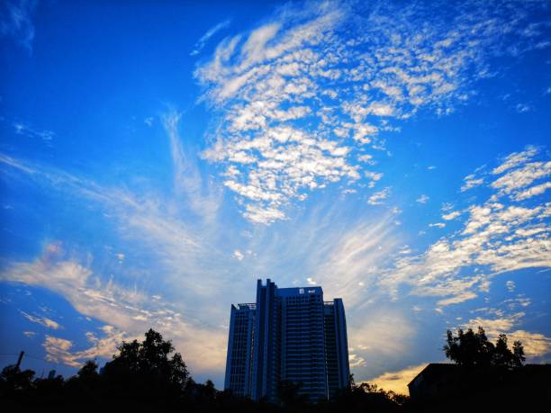 istock white​ cloud​ in​ blue​ sky​ Black​ building​ background 1138613586
