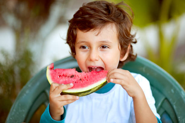 niedliches kind essen gesunde organische wassermelone im sonnigen garten, natur hintergrund - juicy childhood colors red stock-fotos und bilder