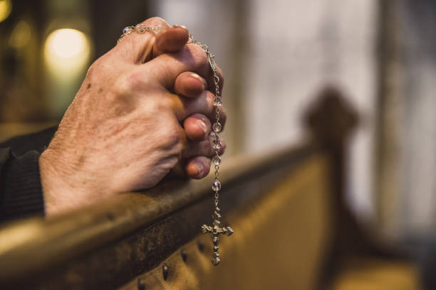 istock Praying hands with rosary in church 1138617050