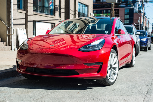 March 26, 2019 - Halifax, Canada - A 2019 red Tesla Model 3 plug-in electric car parked on a city street in downtown Halifax.