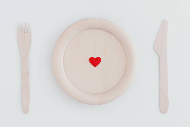 istock Small red heart on wooden plate, fork and knife on white background. Zero waste concept. 1138626007
