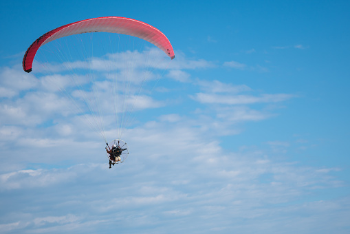 Motor paraglider flying in blue sky