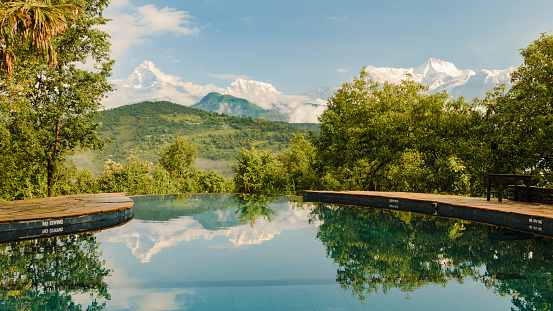 Annapurna mountain range reflecting in an infinity pool in a resort, Pokhara, Nepal.