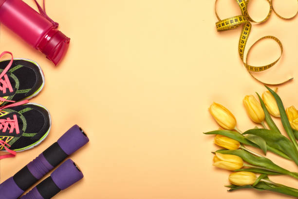 Female fitness background. Female fitness still life. Sport accessories, tulips flowers on yellow background. Mockup. Planning of diet and trainings. Top view with copy space. Healthy lifestyle concept. Slimming 15495 stock pictures, royalty-free photos & images