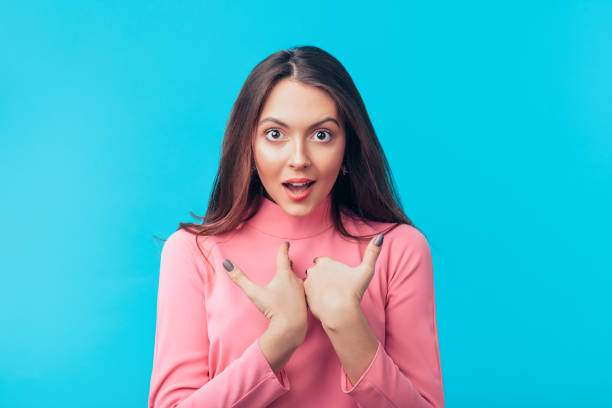 Surprised beautiful woman points at oneself with both hands
