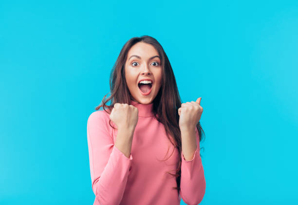 feliz mujer emocionada celebrar el éxito aislado en el fondo azul - behavior shock human face surprise fotografías e imágenes de stock