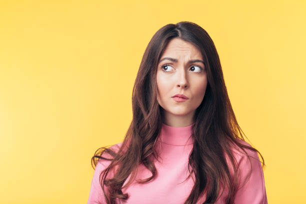 Thoughtful confused woman looking away isolated over yellow background Thoughtful confused woman looking away isolated over yellow background. Doubt concept confused face stock pictures, royalty-free photos & images