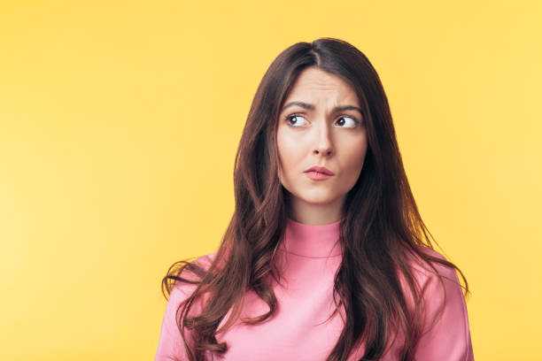 Thoughtful confused woman looking away isolated over yellow background Thoughtful confused woman looking away isolated over yellow background. Doubt concept skeptical look stock pictures, royalty-free photos & images