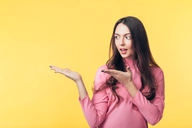 istock Beautiful surprised woman presenting copy space isolated on yellow background 1138637872